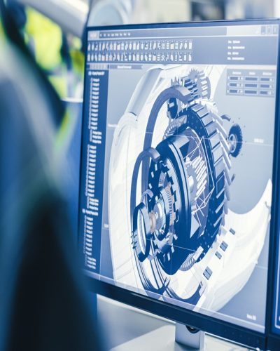 At the Factory: Female Mechanical Engineer Designs 3D Engine on Her Personal Computer while Male Automation Engineer Uses Laptop for Programming Robotic Arm.